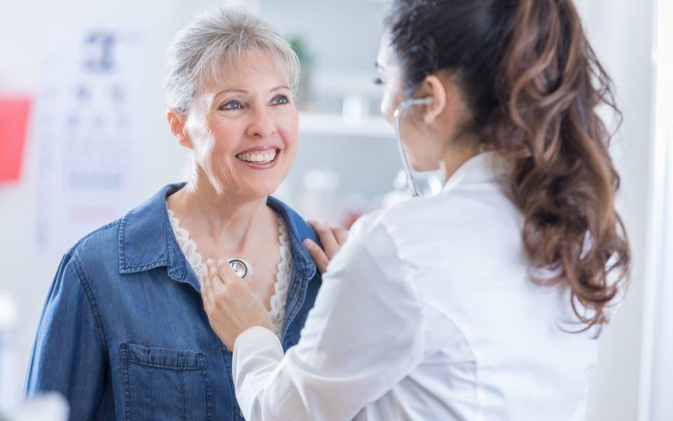 Female physician listens to senior patient's heart